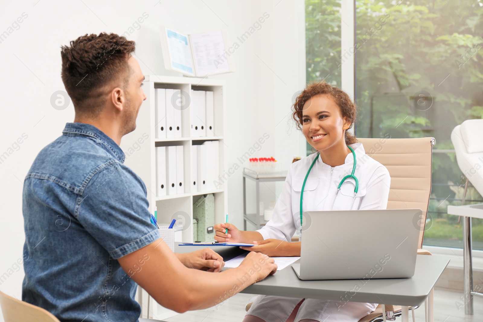 Photo of African American doctor working with patient in hospital