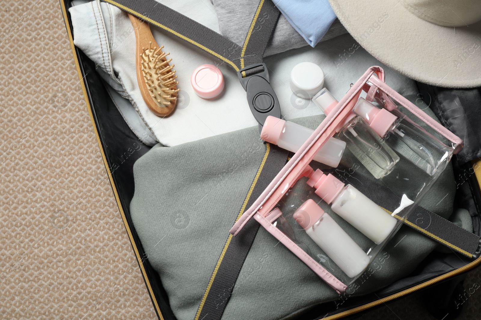 Photo of Plastic bag of cosmetic travel kit in suitcase, top view