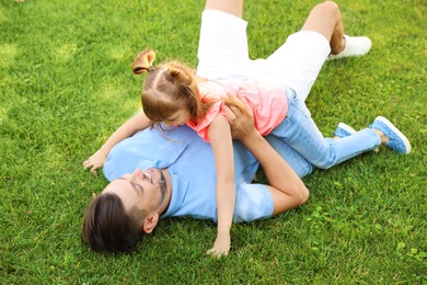 Photo of Father with his cute child on green grass in park. Happy family