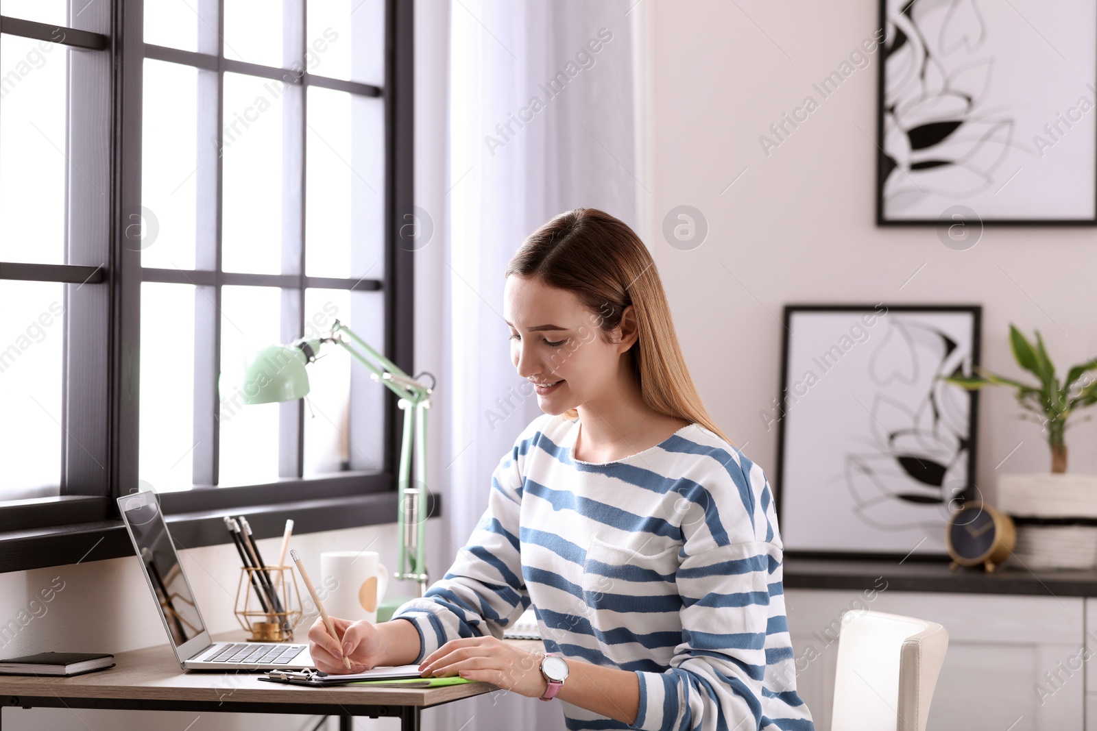 Photo of Teenage girl doing homework at table in her room