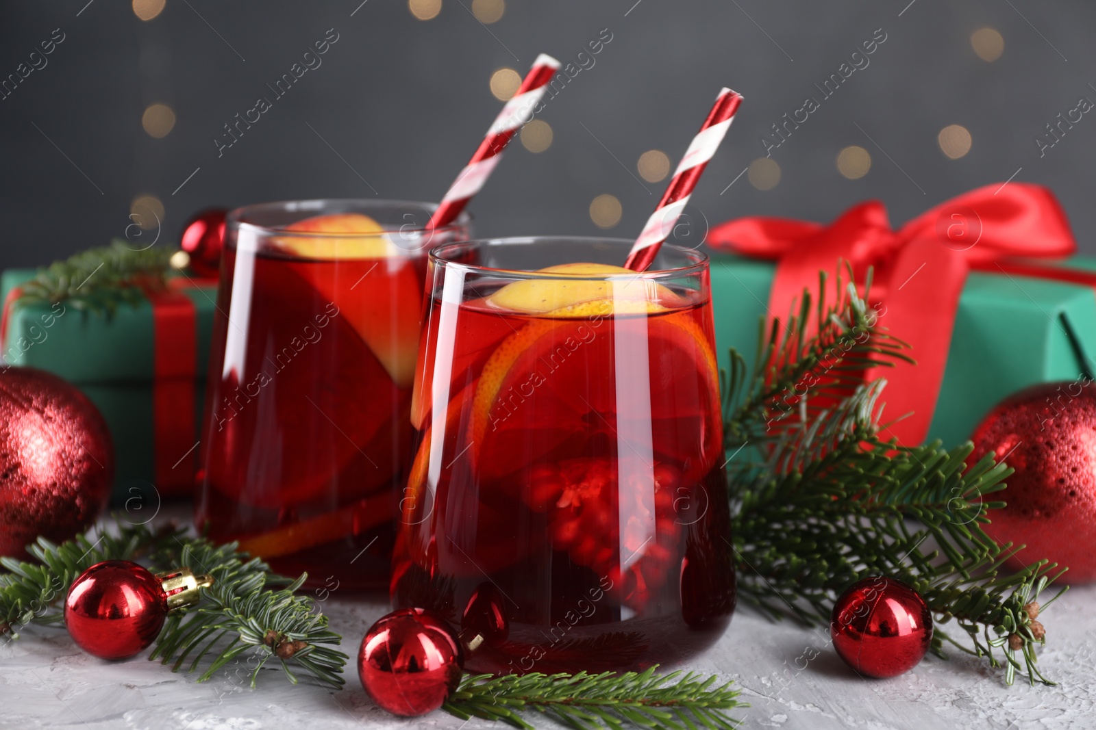 Photo of Delicious Sangria drink in glasses and Christmas decorations on grey textured table, closeup