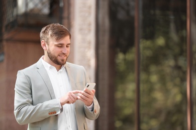 Photo of Portrait of young businessman with smartphone outdoors