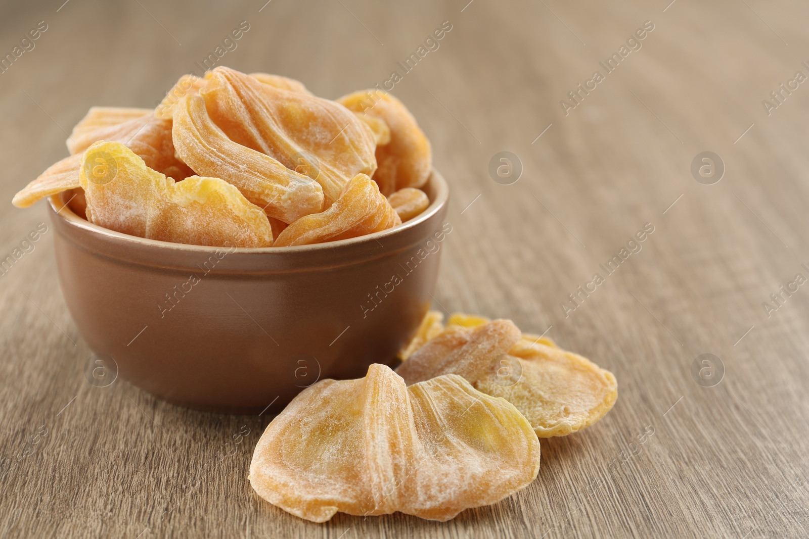 Photo of Delicious dried jackfruit slices on wooden table. Space for text