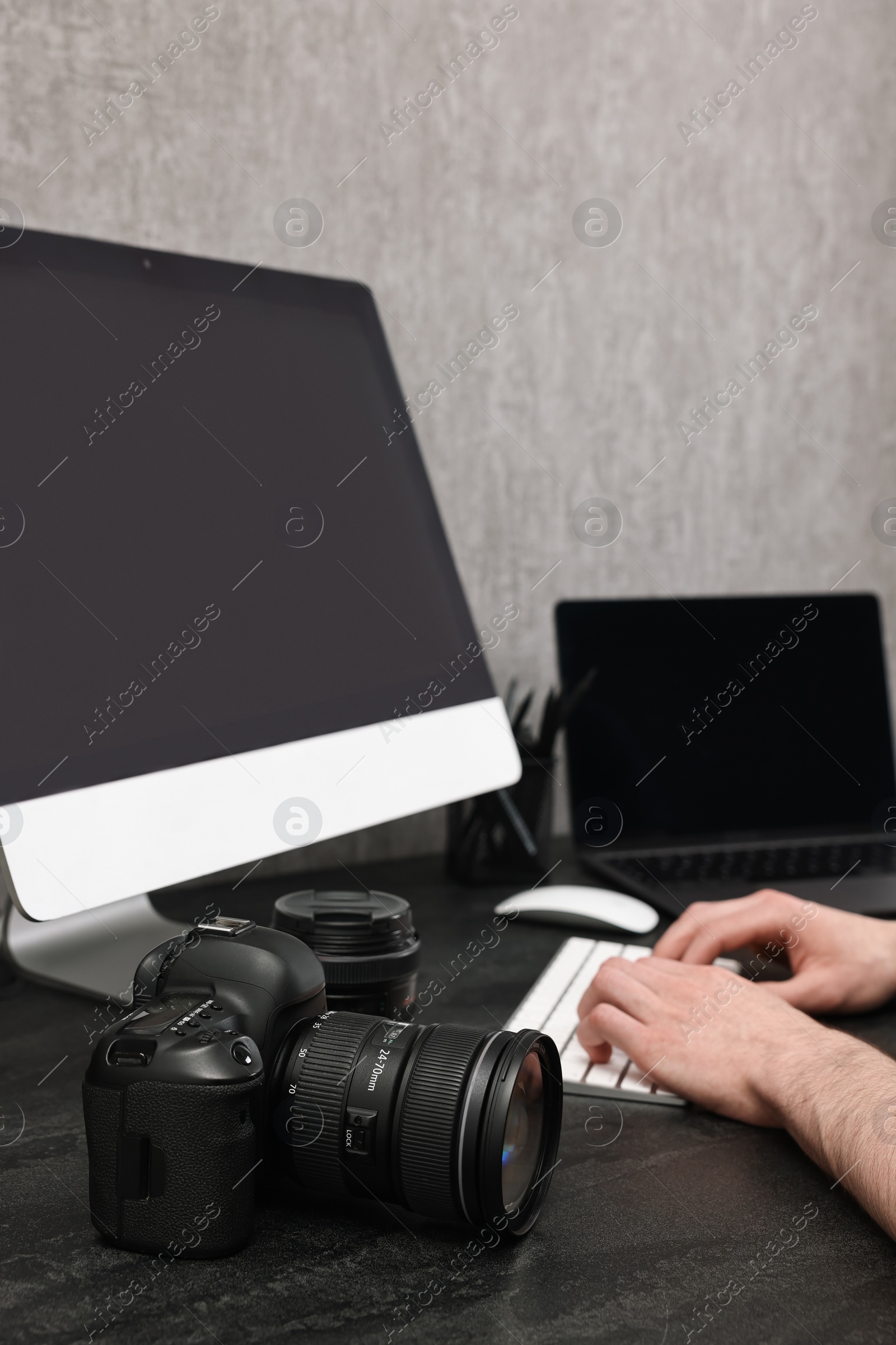 Photo of Photographer working on computer at dark table with camera, closeup