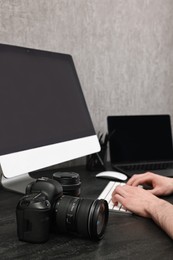 Photographer working on computer at dark table with camera, closeup