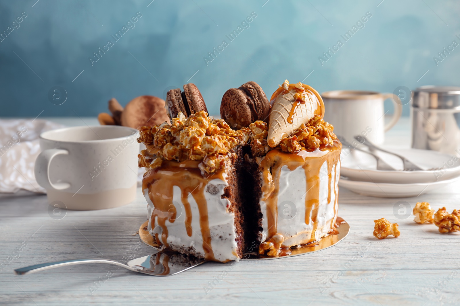 Photo of Delicious homemade cake with caramel sauce and popcorn on table