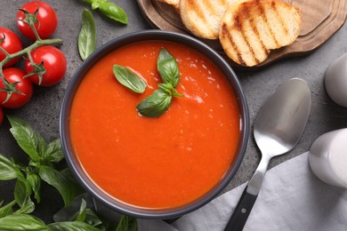 Flat lay composition with delicious tomato cream soup in bowl on grey table