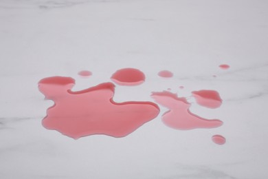 Puddle of red liquid on white marble surface