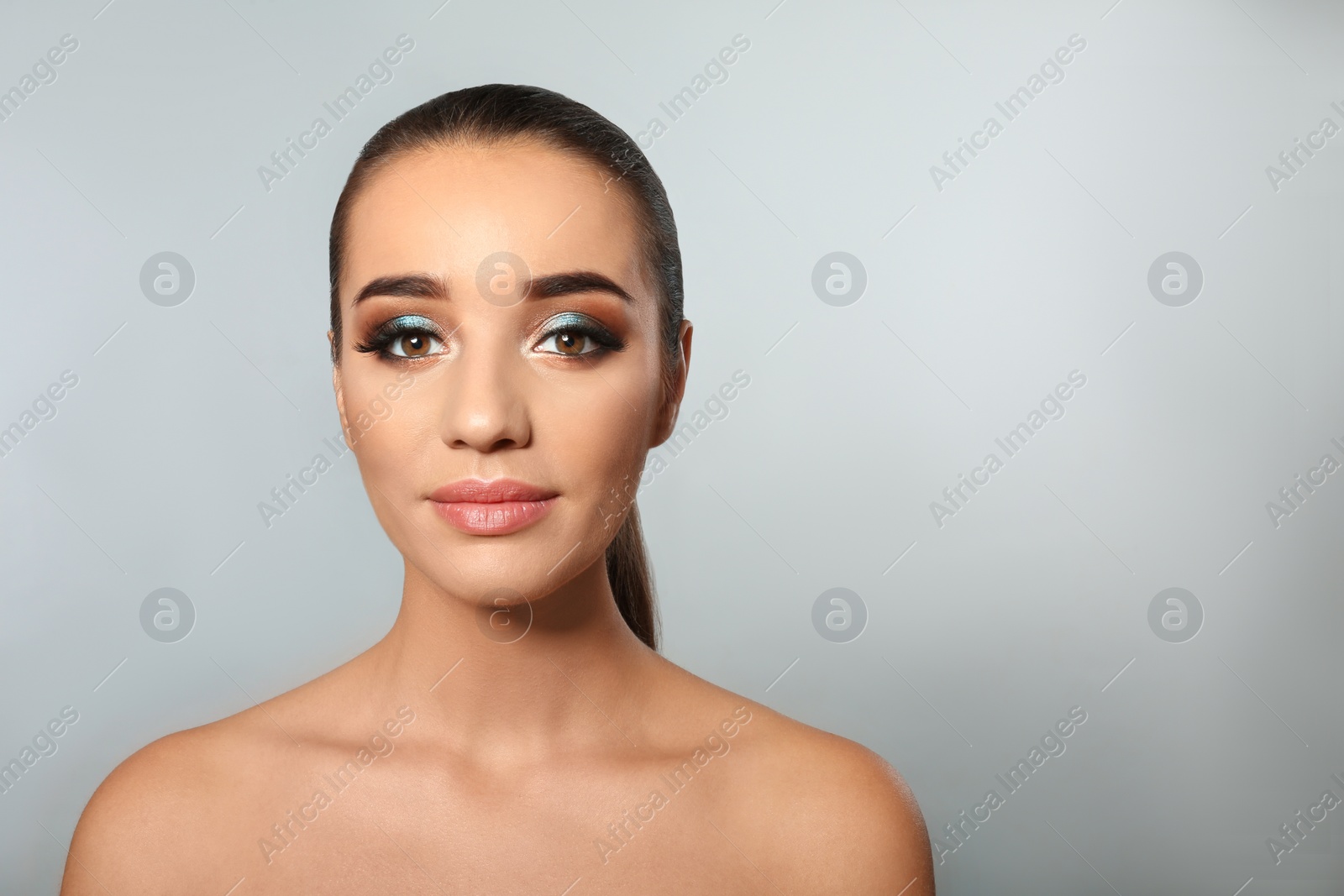 Photo of Portrait of young woman with eyelash extensions and beautiful makeup on light background. Space for text