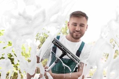 Male cleaner wiping window glass with squeegee from outside