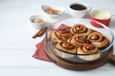 Tasty cinnamon rolls served on white wooden table. Space for text