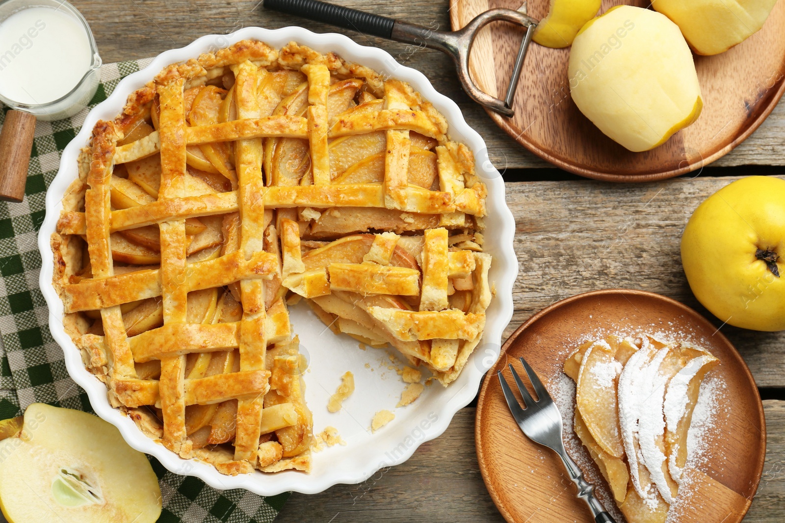 Photo of Tasty homemade quince pie, ingredients, peeler and fork on wooden table, flat lay