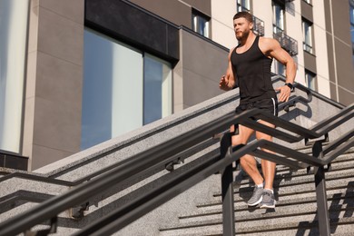 Man running down stairs outdoors on sunny day. Space for text