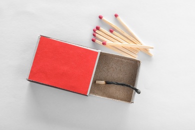 Photo of Cardboard box with burnt match and whole ones on white background, top view. Space for design