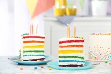 Photo of Delicious rainbow cake with candles for party on table