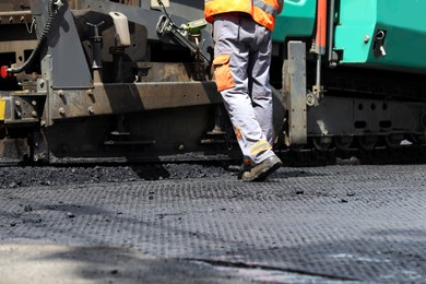 Photo of Worker laying new asphalt with paver, closeup. Road repair