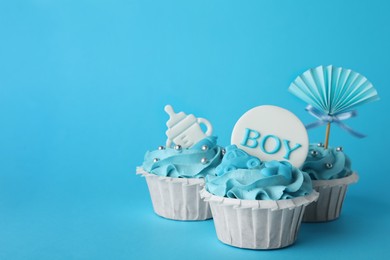 Photo of Baby shower cupcakes with toppers on light blue background, space for text