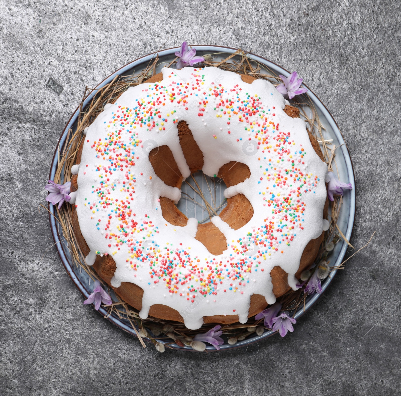 Photo of Glazed Easter cake with sprinkles on grey table, top view