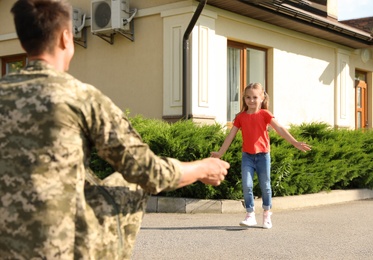 Photo of Father in military uniform and little daughter running to him outdoors