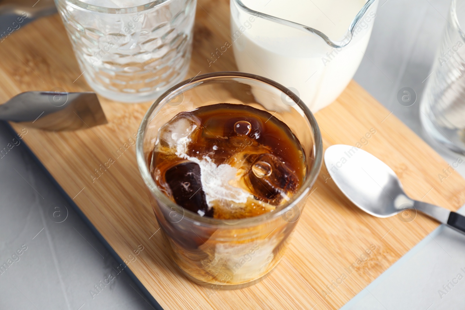 Photo of Glass with cold brew coffee and milk on wooden board