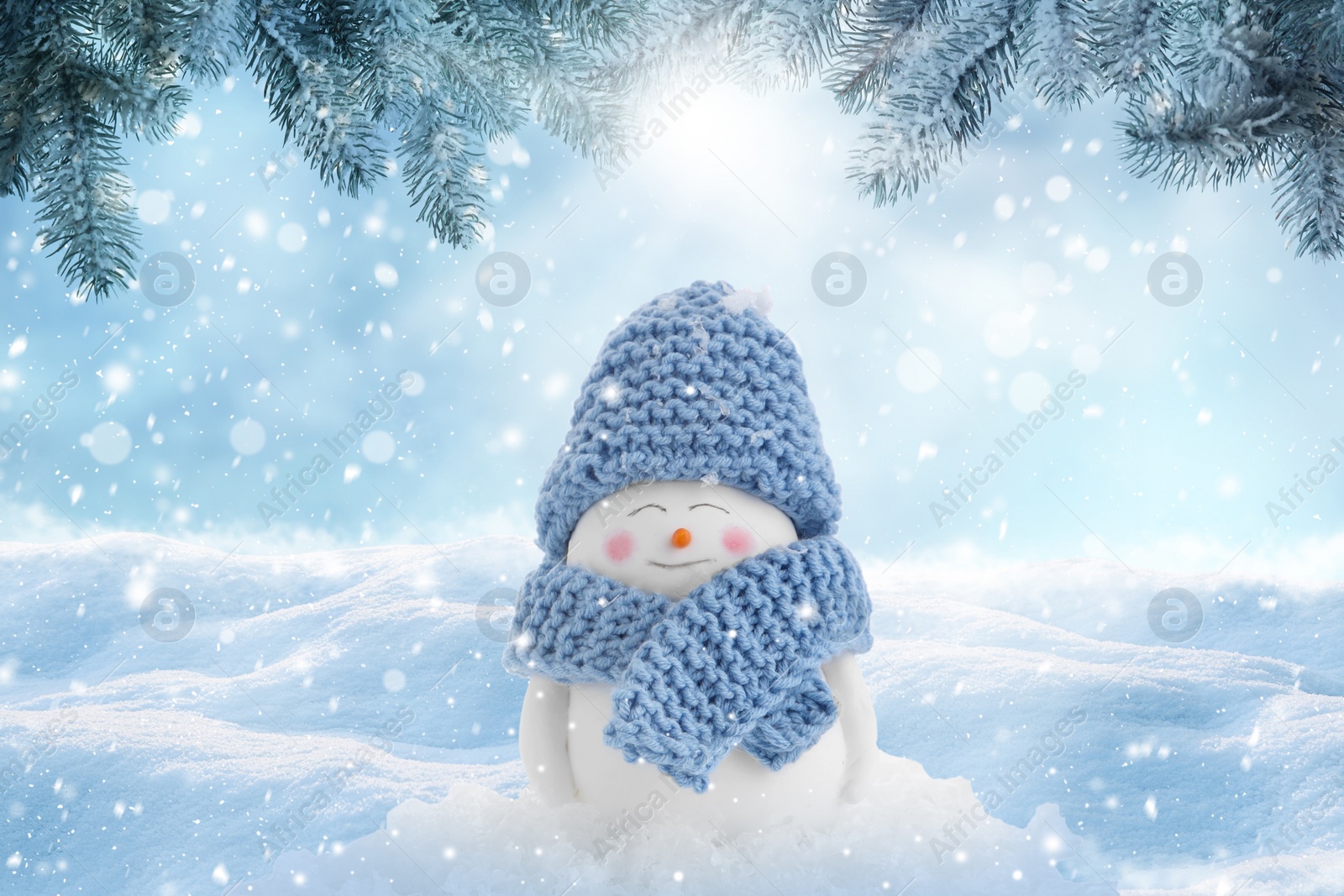 Image of Cute decorative snowman in blue hat and scarf outdoors on snowy day