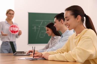 Photo of Happy woman making notes at desk in class during lesson in driving school