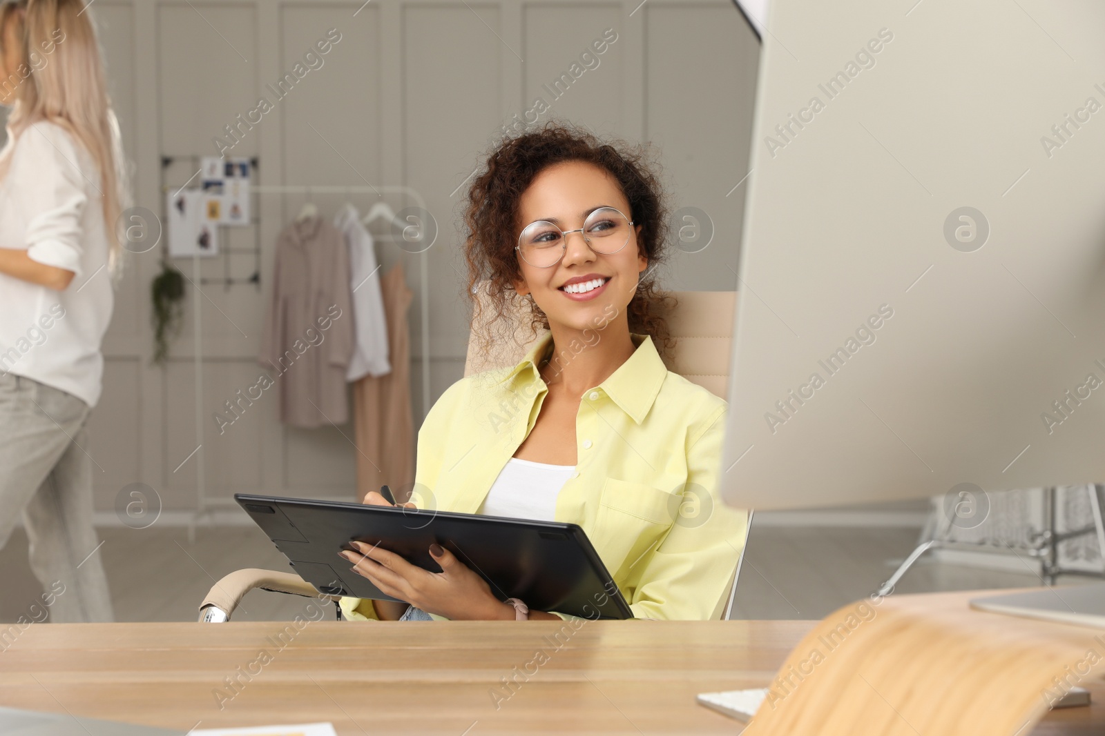 Photo of Professional African American retoucher working with graphic tablet at desk in photo studio