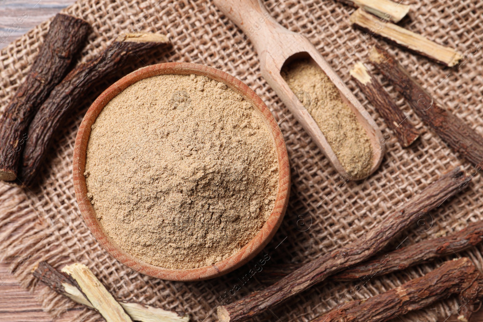 Photo of Dried sticks of liquorice root and powder on wooden table, flat lay