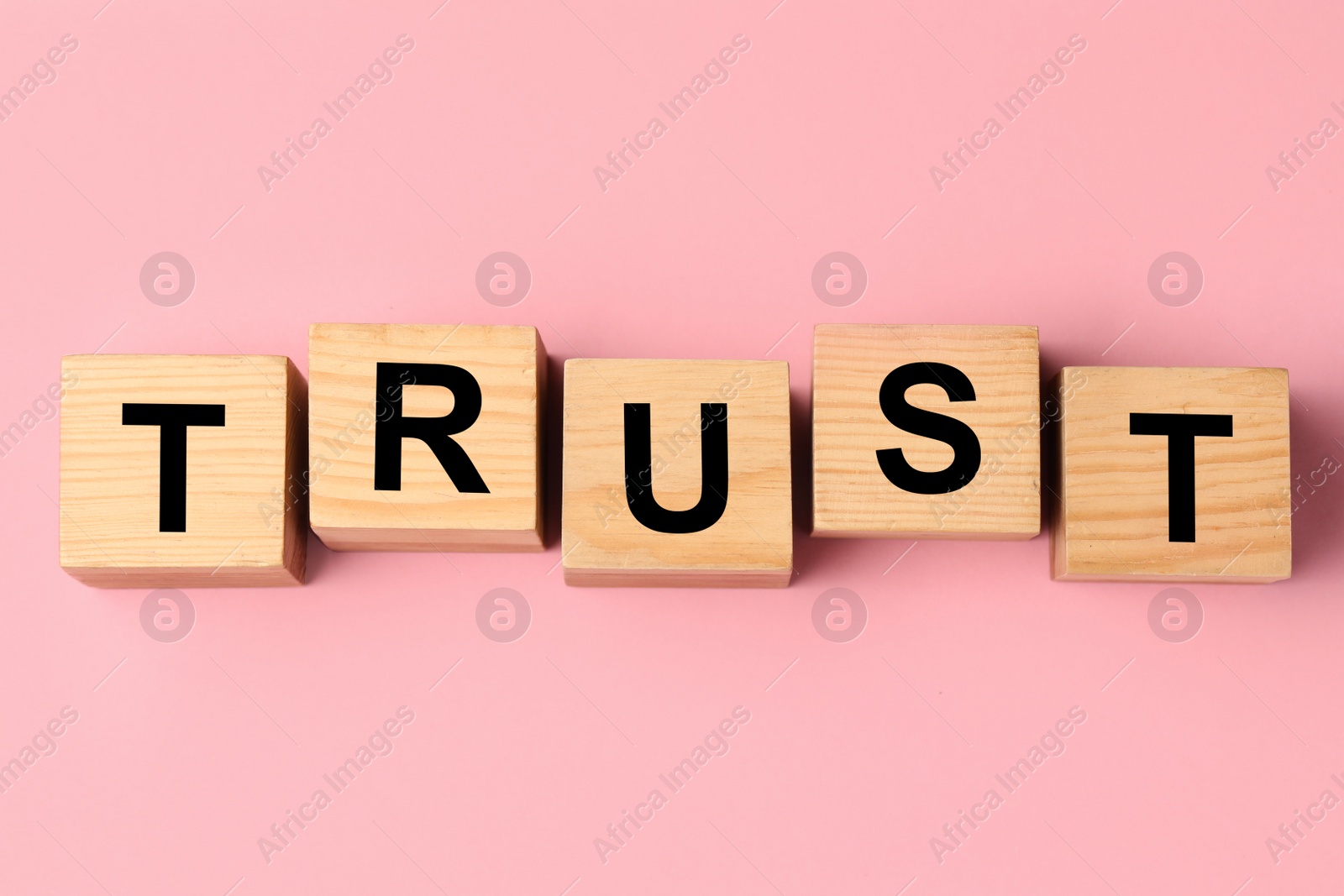 Photo of Cubes with word TRUST on pink background, flat lay