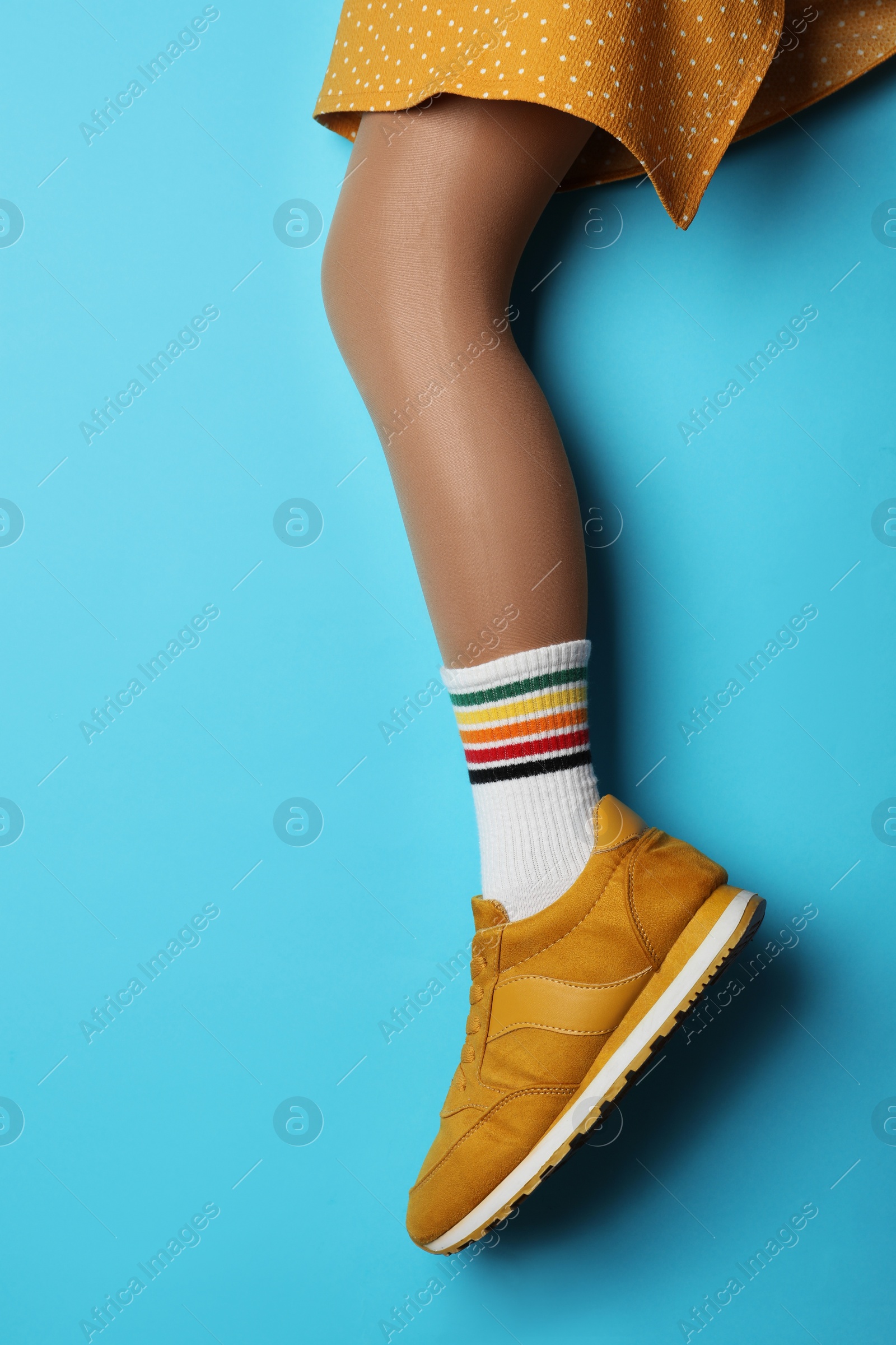 Photo of Woman wearing sneakers on light blue background, closeup