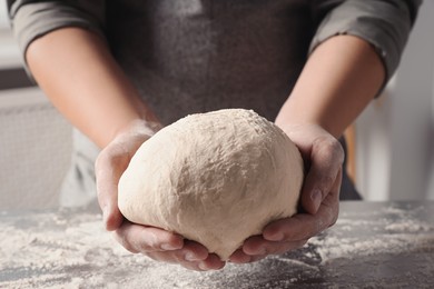 Photo of Man kneading dough at table in kitchen, closeup