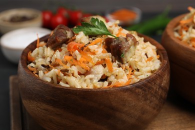 Delicious pilaf with meat and carrot in bowl on table, closeup