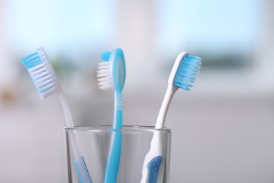 Photo of Plastic toothbrushes in holder on blurred background, closeup