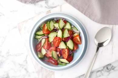 Bowl of vegetarian salad with cucumber, tomato and onion served on table, flat lay