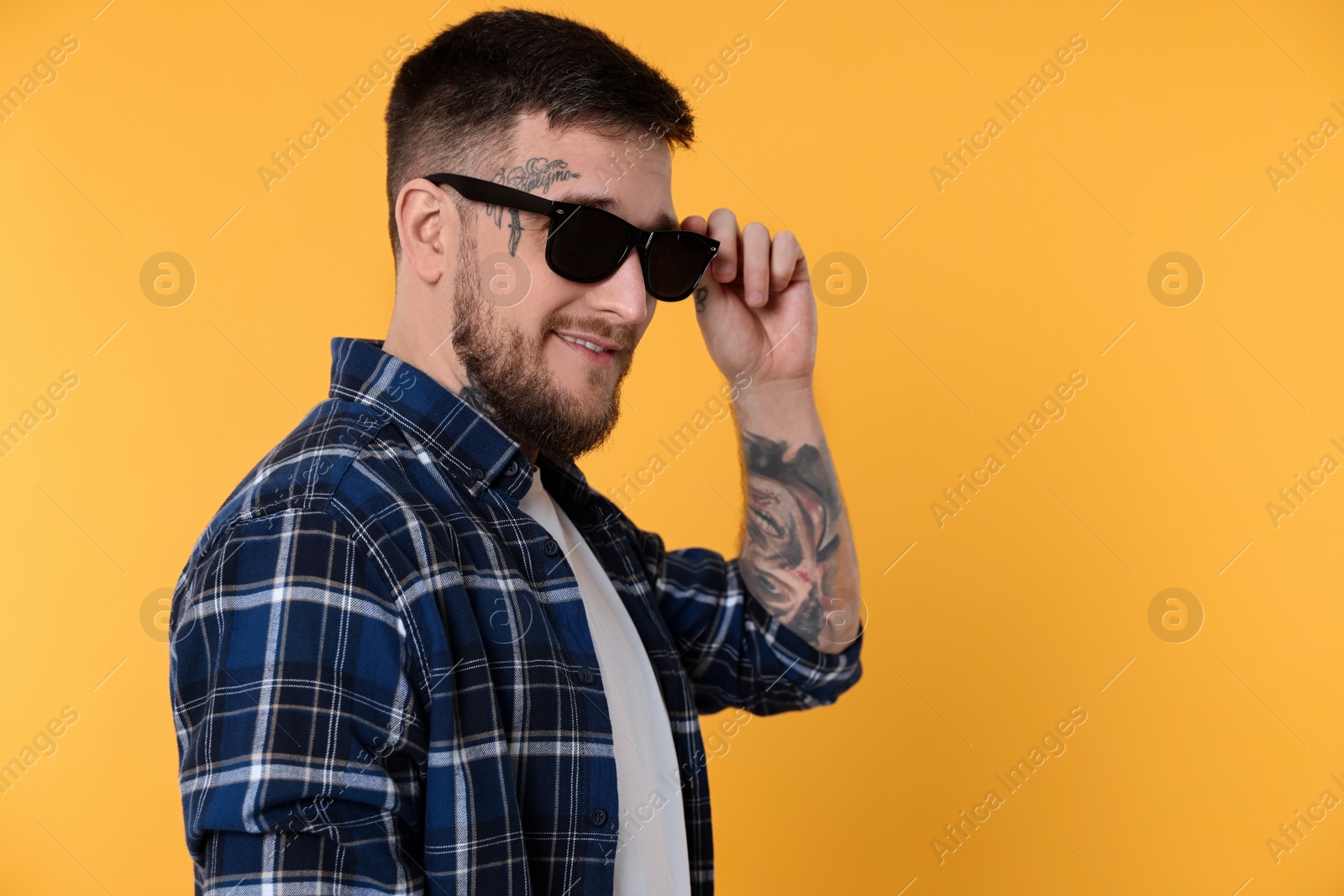 Photo of Handsome hipster man wearing stylish sunglasses on yellow background. Space for text