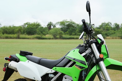Stylish cross motorcycle on green grass outdoors