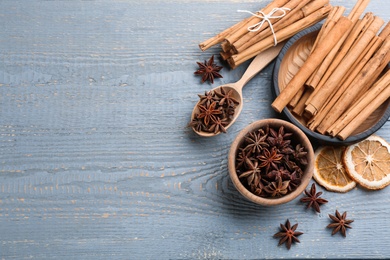 Aromatic cinnamon sticks and anise on grey wooden table, flat lay. Space for text