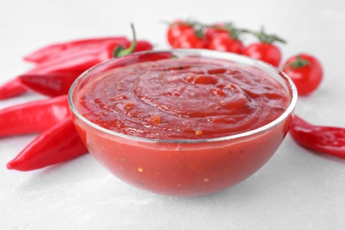 Bowl of hot chili sauce and vegetables on table, closeup