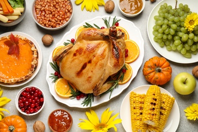 Photo of Traditional Thanksgiving day feast with delicious cooked turkey and other seasonal dishes served on grey table, flat lay