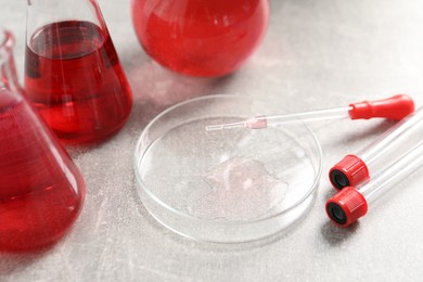 Photo of Laboratory analysis. Different glassware with red liquid on light grey table