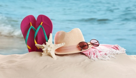 Image of Different beach accessories on sand near ocean