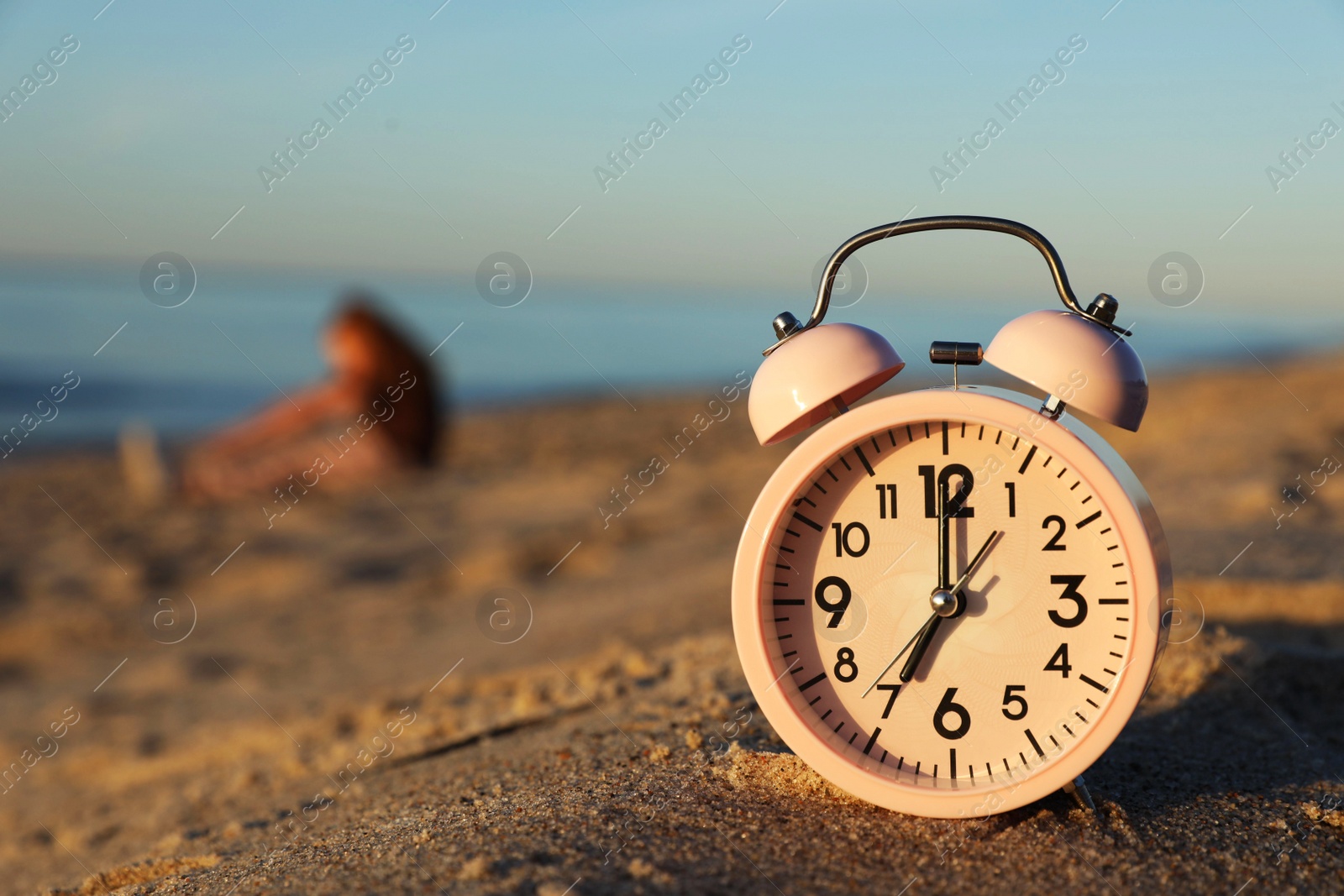 Photo of Woman doing morning exercises near river outdoors, focus on alarm clock