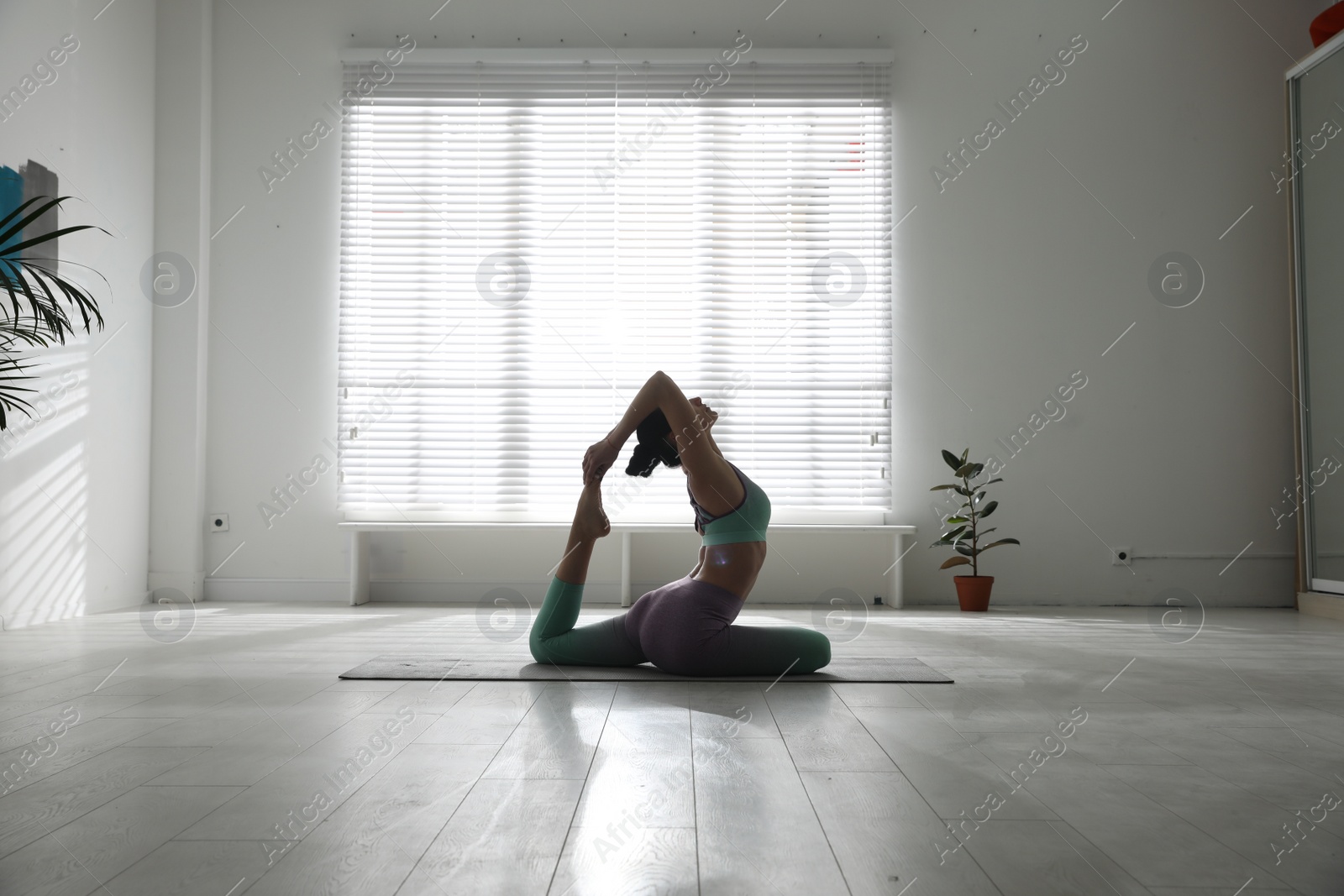 Photo of Woman practicing one legged king pigeon asana in yoga studio. Eka pada rajakapotasana pose