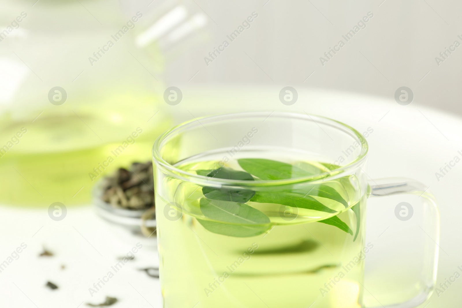 Photo of Cup of aromatic green tea with leaves on light background, closeup