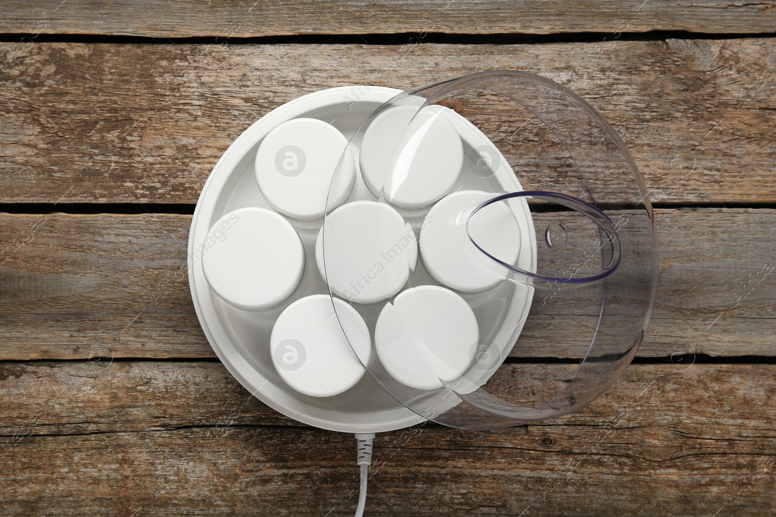 Photo of Modern yogurt maker with jars on wooden table, top view