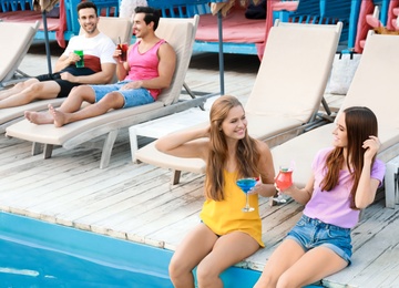 Photo of Happy young friends with fresh summer cocktails relaxing near swimming pool