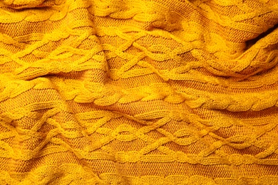 Photo of Soft orange knitted plaid as background, top view
