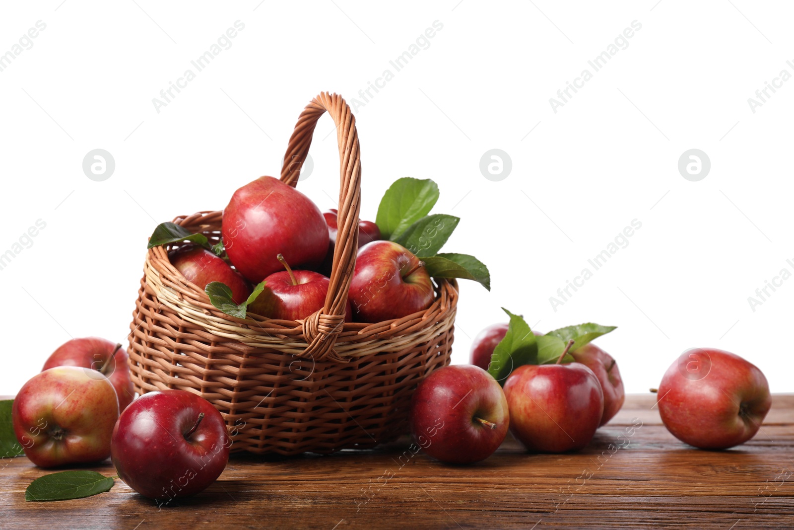 Photo of Ripe red apples and leaves on wooden table against white background