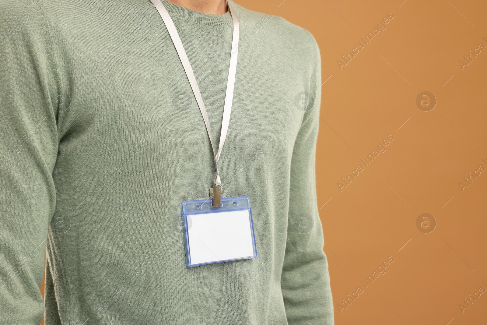 Photo of Man with blank badge on light brown background, closeup. Space for text