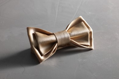 Photo of Stylish pale yellow bow tie on gray textured background